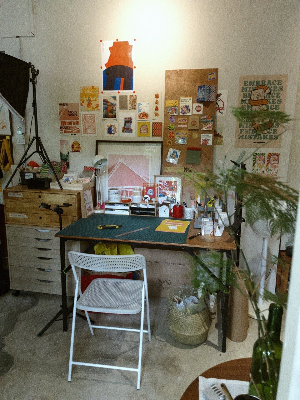 Monny Reak studio with cutting mat, pinned sketches, and Embrace Mistakes poster